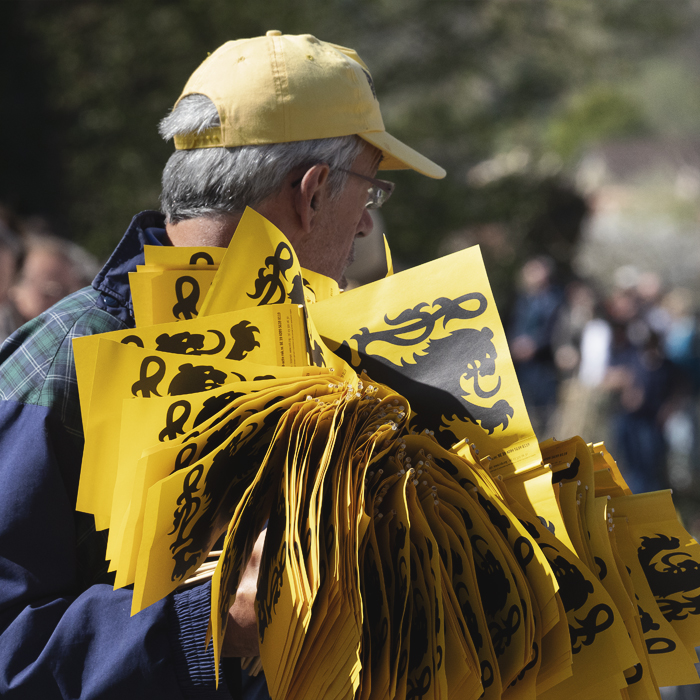 Ronde van Vlaanderen 2025 - A man, his arms laden with flags of Flanders to give out to the crowds