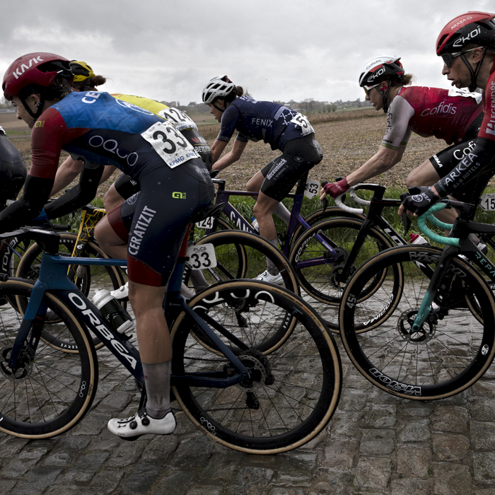 Ronde van Vlaanderen Vrouwen 2024 - A side view of riders on the wet cobbles of Mariaborrestraat