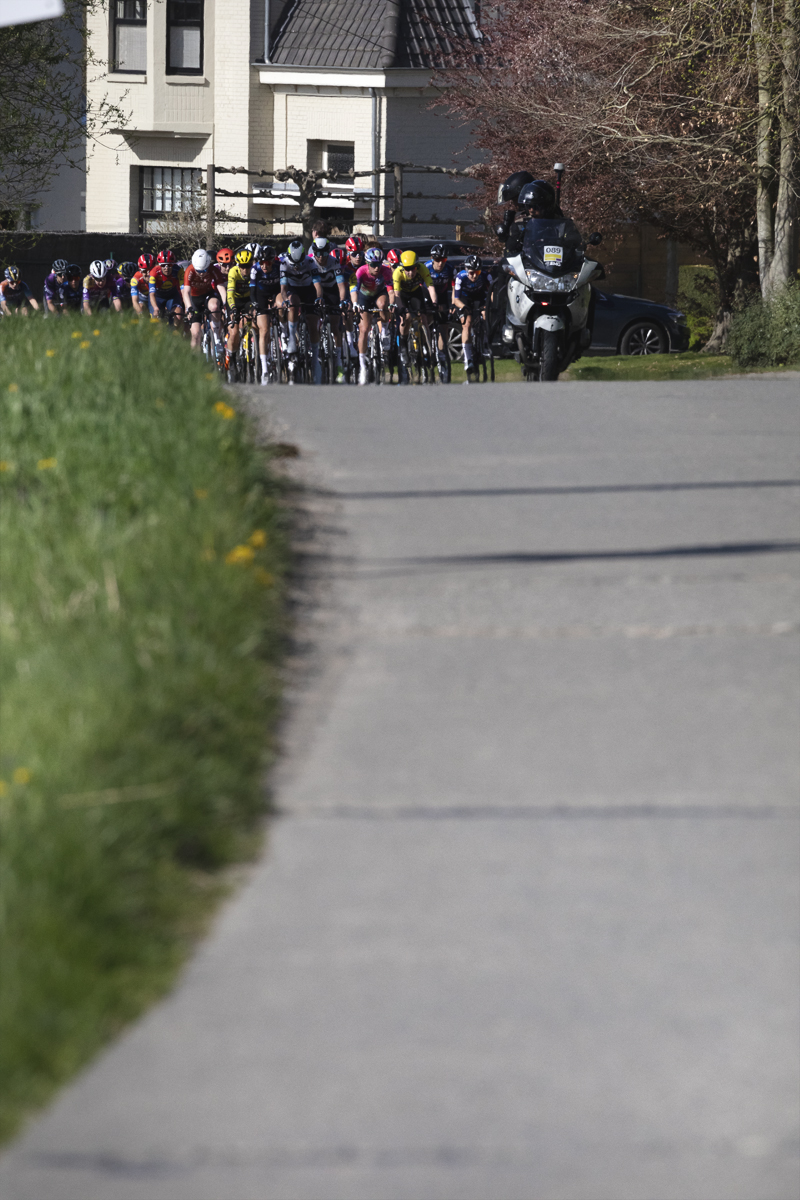 Ronde van Vlaanderen Vrouwen 2025 - Riders approach down a long concrete road in Maarkedal