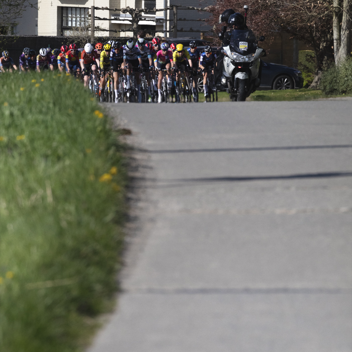 Ronde van Vlaanderen Vrouwen 2025 - Riders approach down a long concrete road in Maarkedal