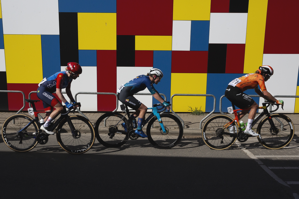 Ronde van Vlaanderen Vrouwen 2025 - Riders pass a brightly coloured, Mondrian style wall Michelbeke