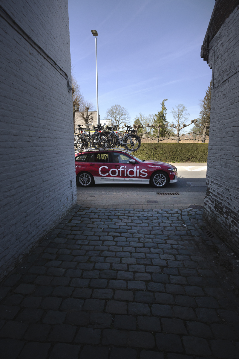 Ronde van Vlaanderen Vrouwen 2025 - A Cofidis team car is framed by an alleyway entrance