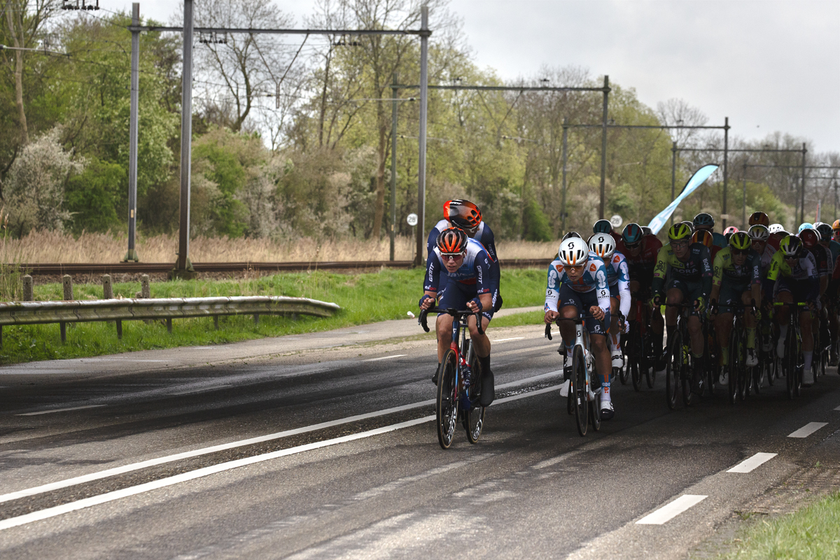 Scheldeprijs 2024 - A group of riders race past train lines near Rilland