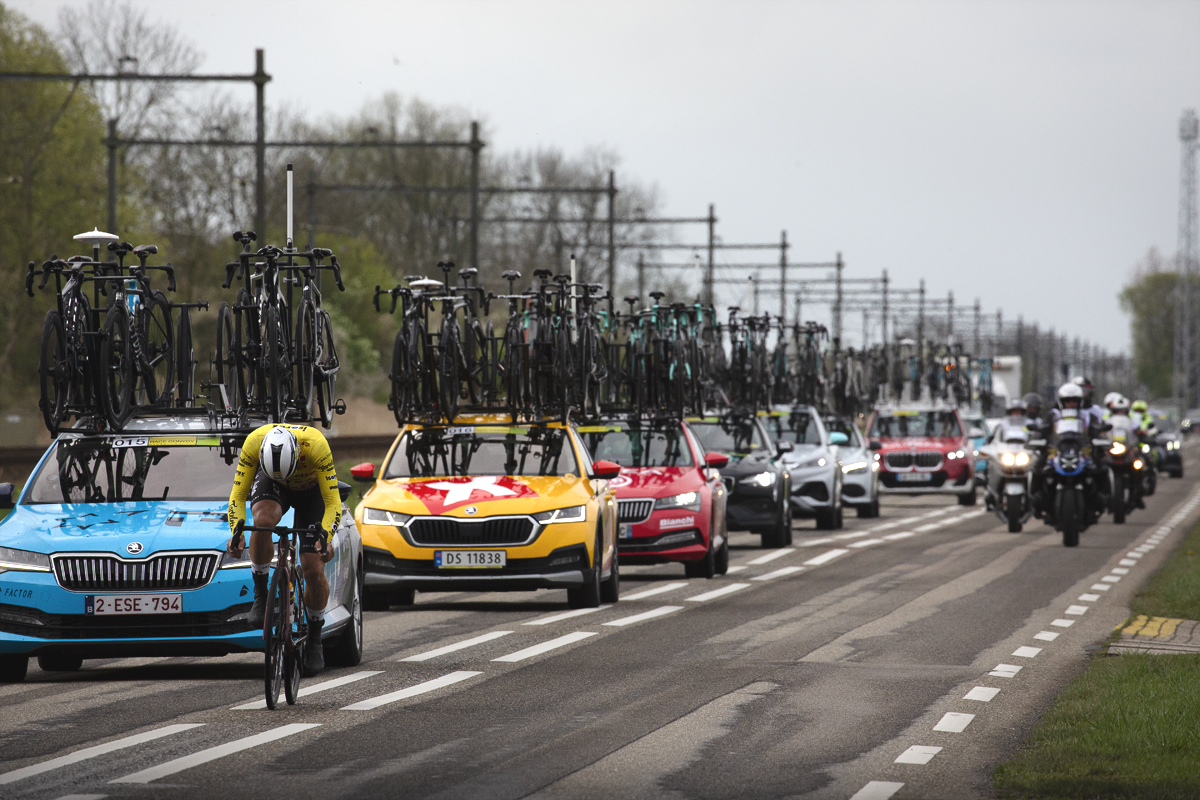 Scheldeprijs 2024 - A rider with his head down in a convoy of team cars near Rilland