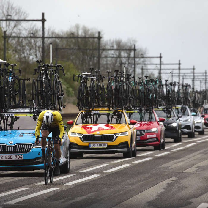 Scheldeprijs 2024 - A rider with his head down in a convoy of team cars near Rilland