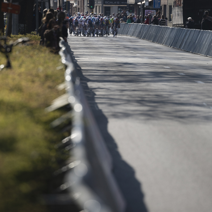 Scheldeprijs 2025 - The peloton sprints down the barrier lined finish straight in Schoten