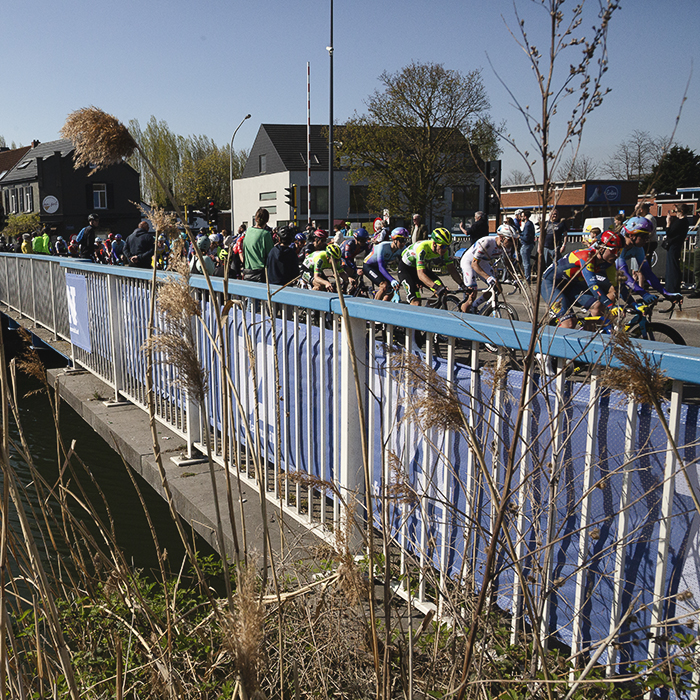 Scheldeprijs 2025 - Riders pass over a canal bridge on the circuit in Schoten
