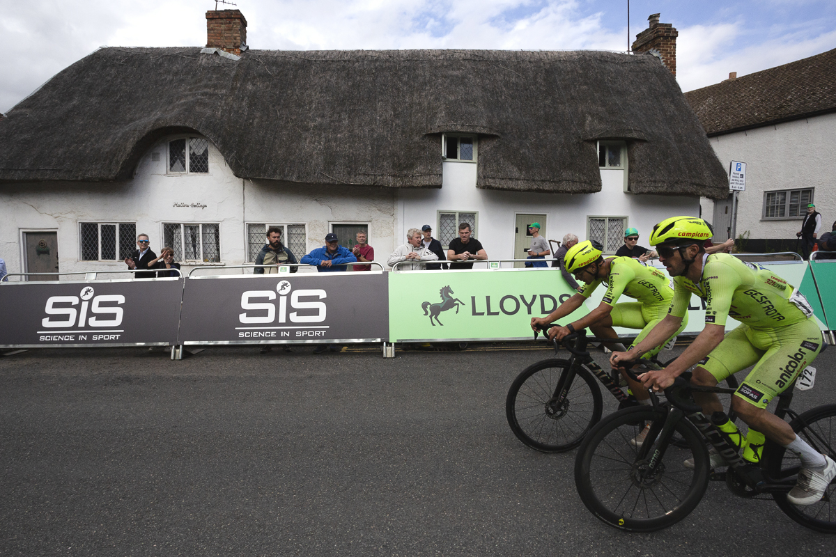 Tour of Britain 2025 - Alexis Guerin & Paulo Fernandes ride in front of a white thatched cottage