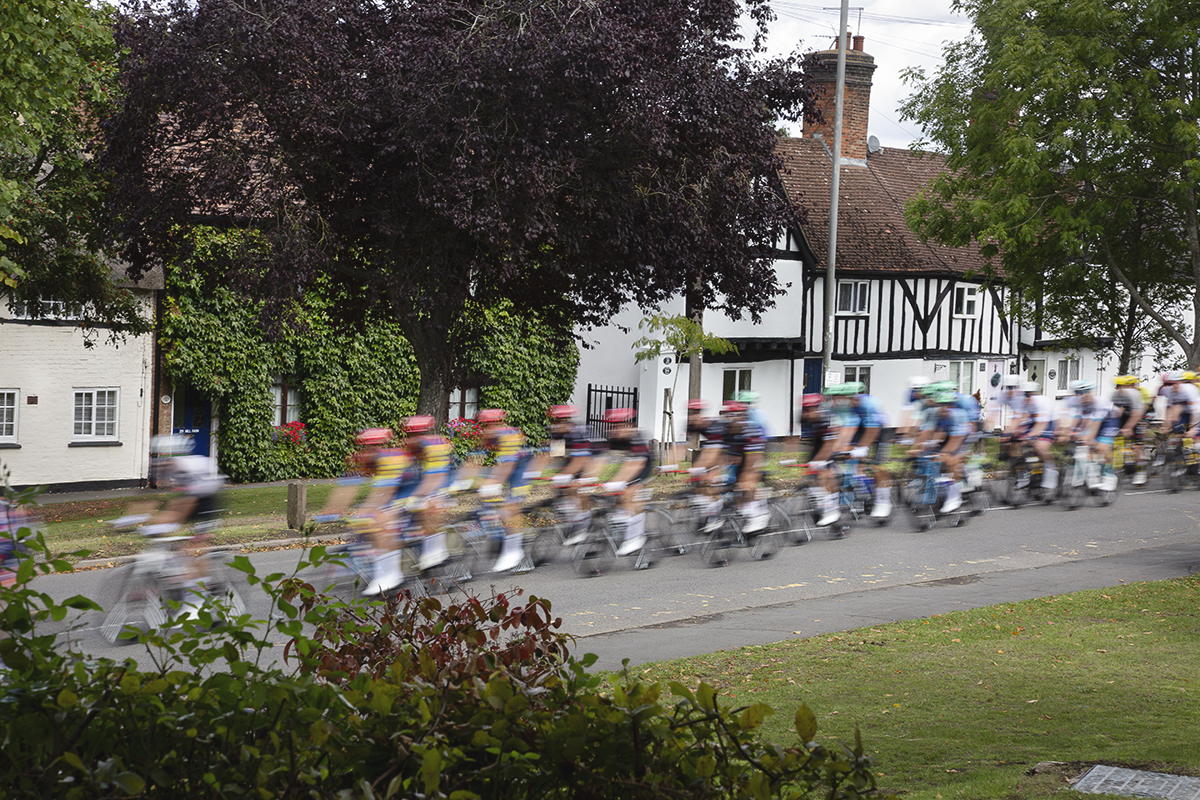 Tour of Britain 2025 - Riders speed past a row of white cottages in Brinklow