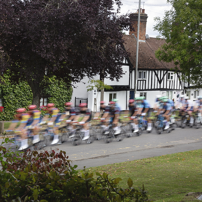 Tour of Britain 2025 - Riders speed past a row of white cottages in Brinklow