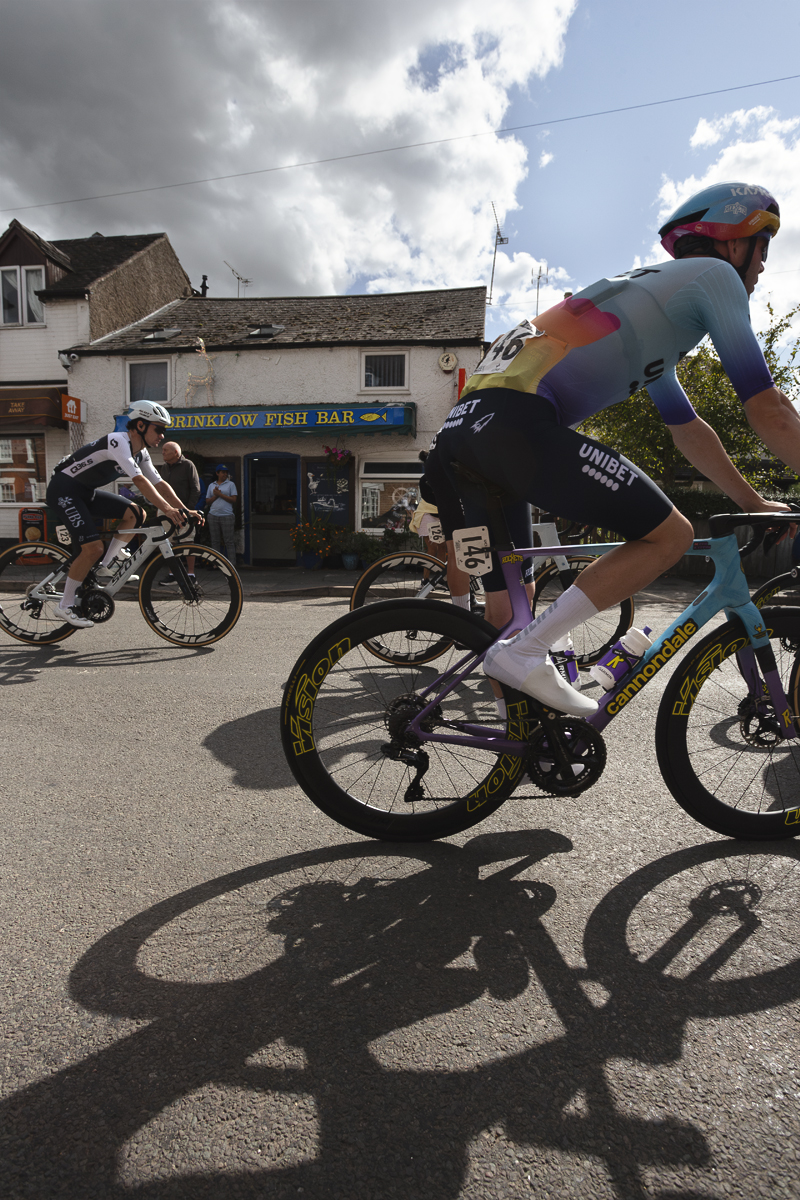 Tour of Britain 2025 - Joe Pidcock & Zeb Kyffin ride past a chip shop in Brinklow