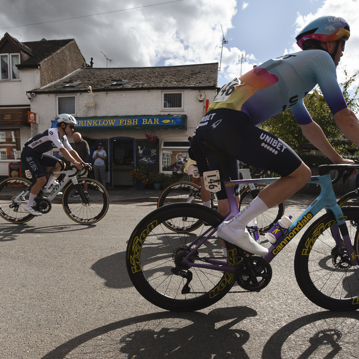 Tour of Britain 2025 - Joe Pidcock & Zeb Kyffin ride past a chip shop in Brinklow