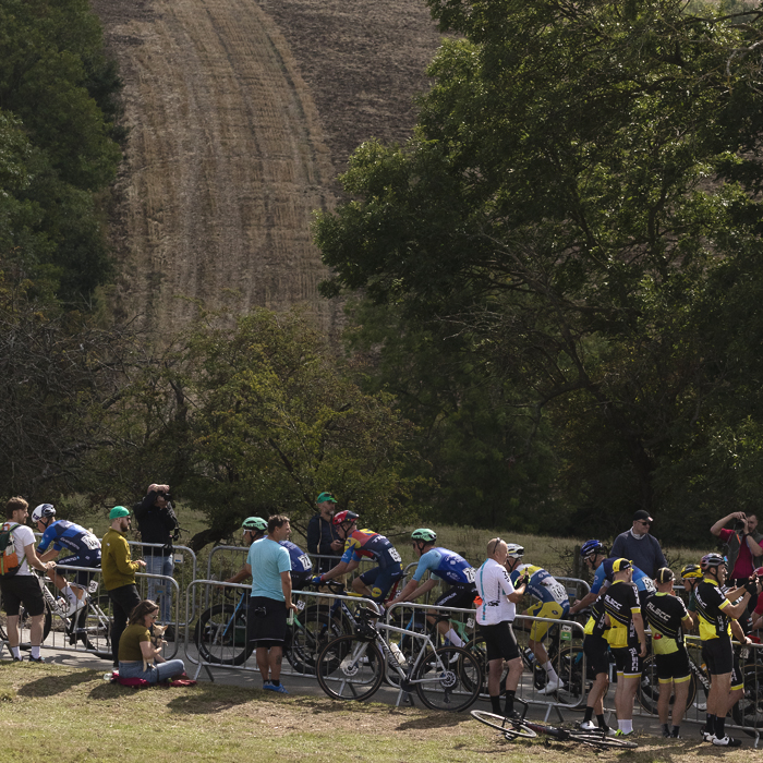 Tour of Britain 2025 - Riders pass groups of fans at the roadside in Burton Dassett with countryside behind them