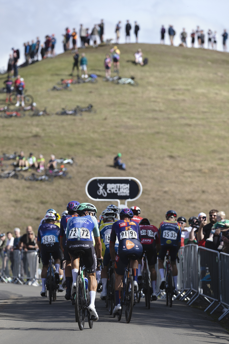 Tour of Britain 2025 - Dries De Bondt looks towards the crowds of fans with the crest of the hill lined with people in front