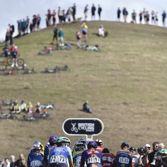 Tour of Britain 2025 - Dries De Bondt looks towards the crowds of fans with the crest of the hill lined with people in front