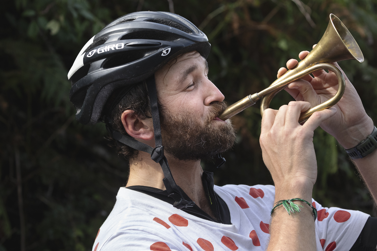 Tour of Britain 2025 - A fan wearing a King of the Mountain’s polka dot jersey blows a bugle