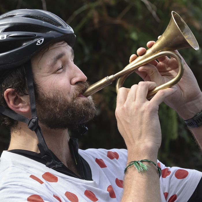 Tour of Britain 2025 - A fan wearing a King of the Mountain’s polka dot jersey blows a bugle