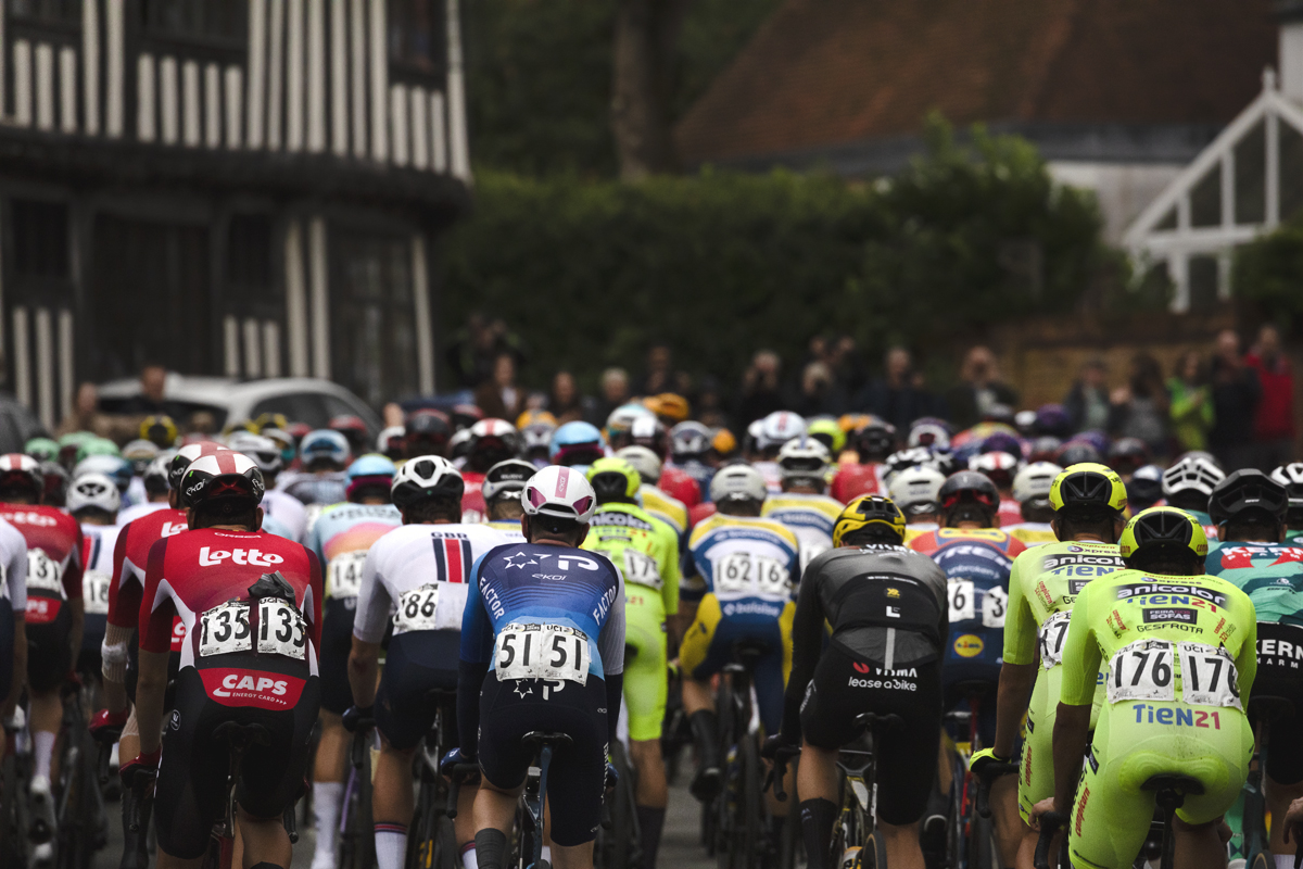 Tour of Britain 2025 - A rear view of riders passing timber framed buildings in Lavenham