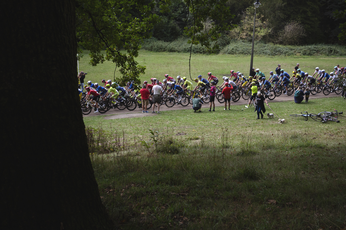 Tour of Britain 2025 - Fans watch the peloton as dog walkers pass by in Pontypool Park