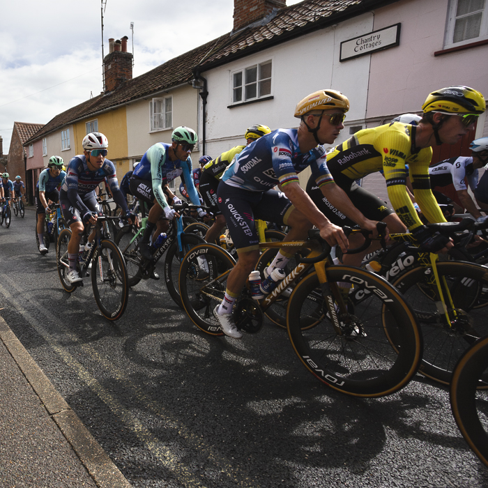 Tour of Britain 2025 - The peloton passed pastel coloured cottages in Saxmundham
