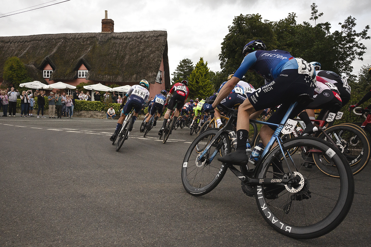 Tour of Britain 2025 - Riders round the corner near the Four Horseshoes thatched pub at Thornham Magna