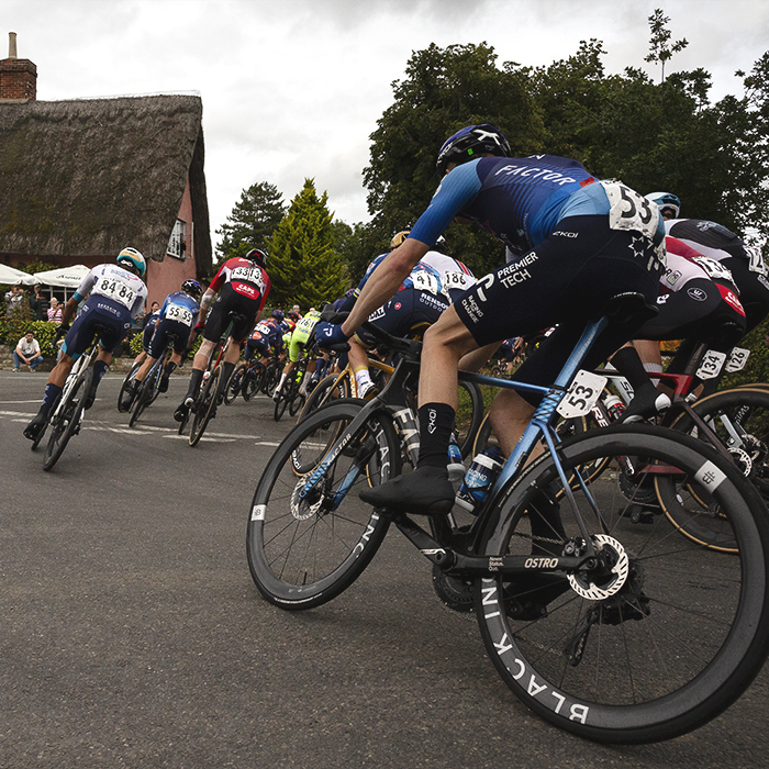 Tour of Britain 2025 - Riders round the corner near the Four Horseshoes thatched pub at Thornham Magna