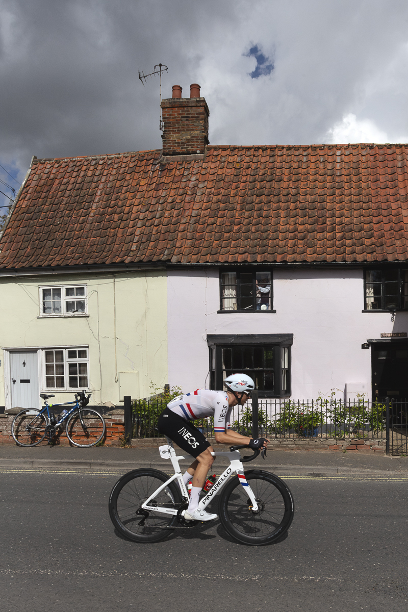 Tour of Britain 2025 - Sam Watson rides past pastel painted cottages in Wickham Market
