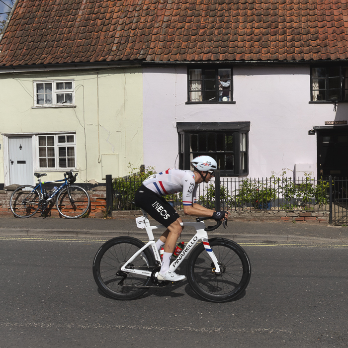 Tour of Britain 2025 - Sam Watson rides past pastel painted cottages in Wickham Market