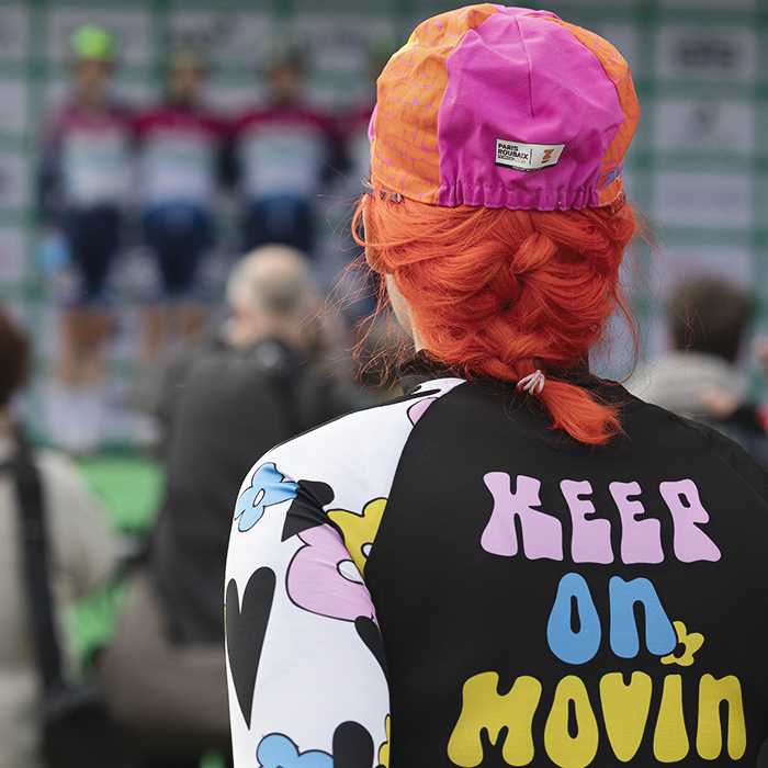 Tour of Britain Women’s 2025 - Stage 4 - A fan with bright orange hair and a top that reads Keep On Movin’ watches the presentation of teams before the stage in Glasgow