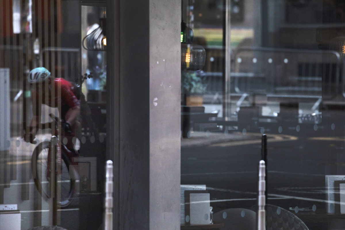 Tour of Britain Women’s 2025 - Stage 4 - A rider reflected in the glazed facade of a restaurant