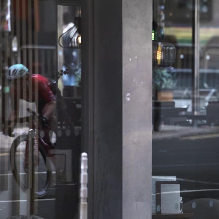 Tour of Britain Women’s 2025 - Stage 4 - A rider reflected in the glazed facade of a restaurant