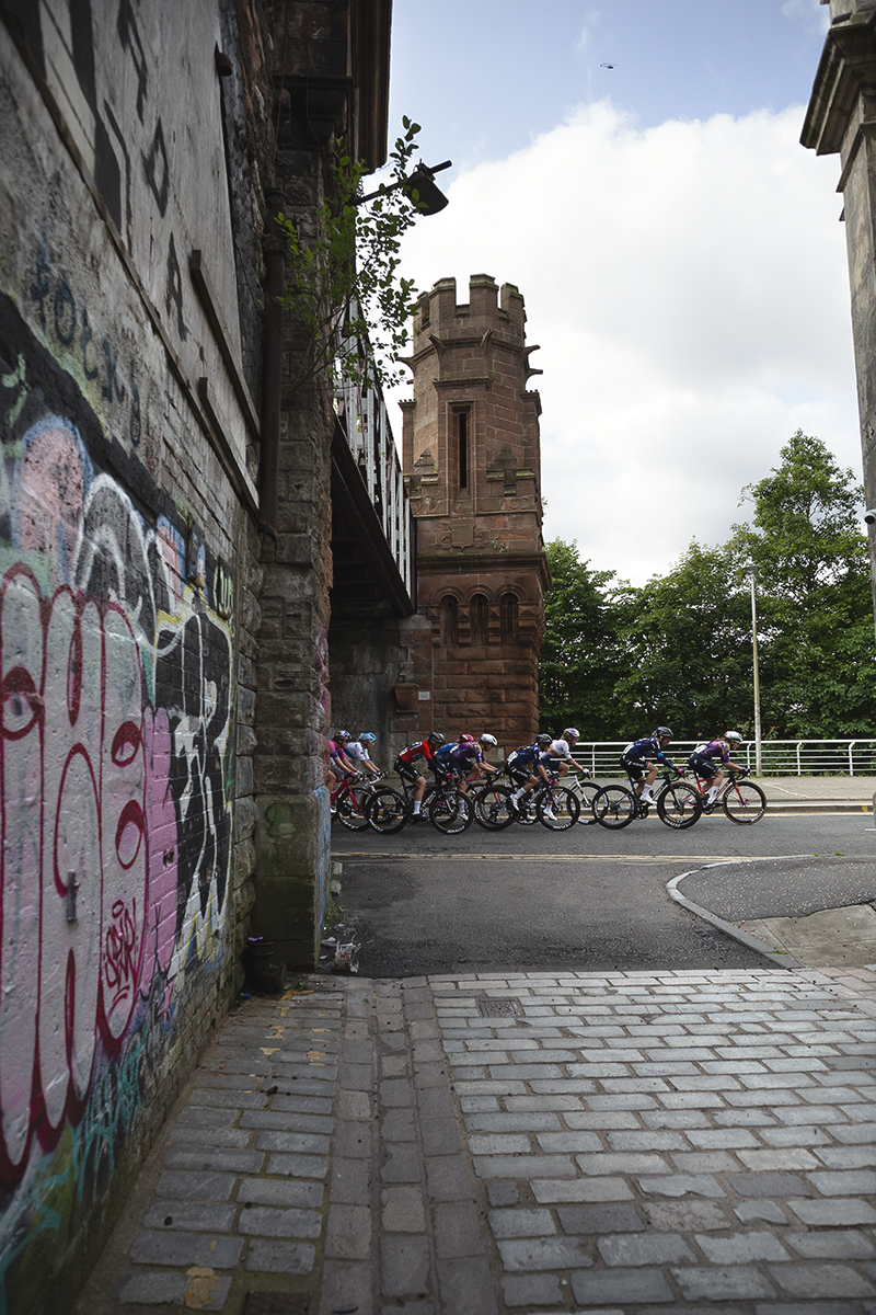 Tour of Britain Women’s 2025 - Stage 4 - The peloton on Clyde Street as seen from Merchant Lane  with grafitti in the foreground