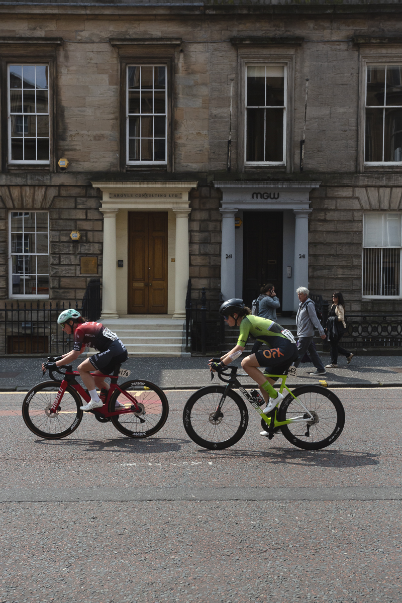 Tour of Britain Women’s 2025 - Stage 4 - Jo Tindley & Holly Ramsey pass two stone buildings with grand entrances