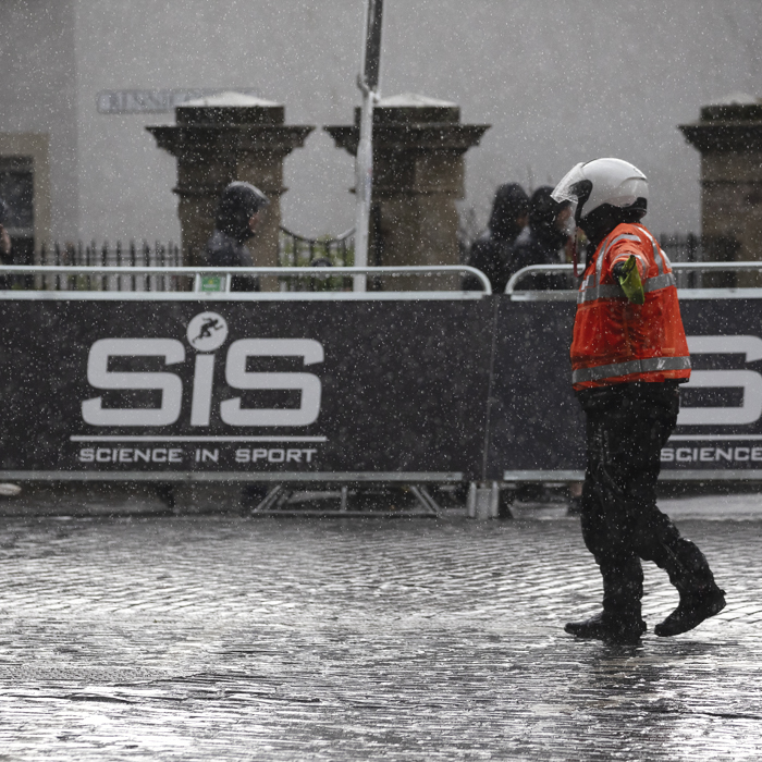 Tour of Britain Women’s 2025 - Stage 3 - Race staff direct vehicles to the deviation point in the pouring rain at Kelso