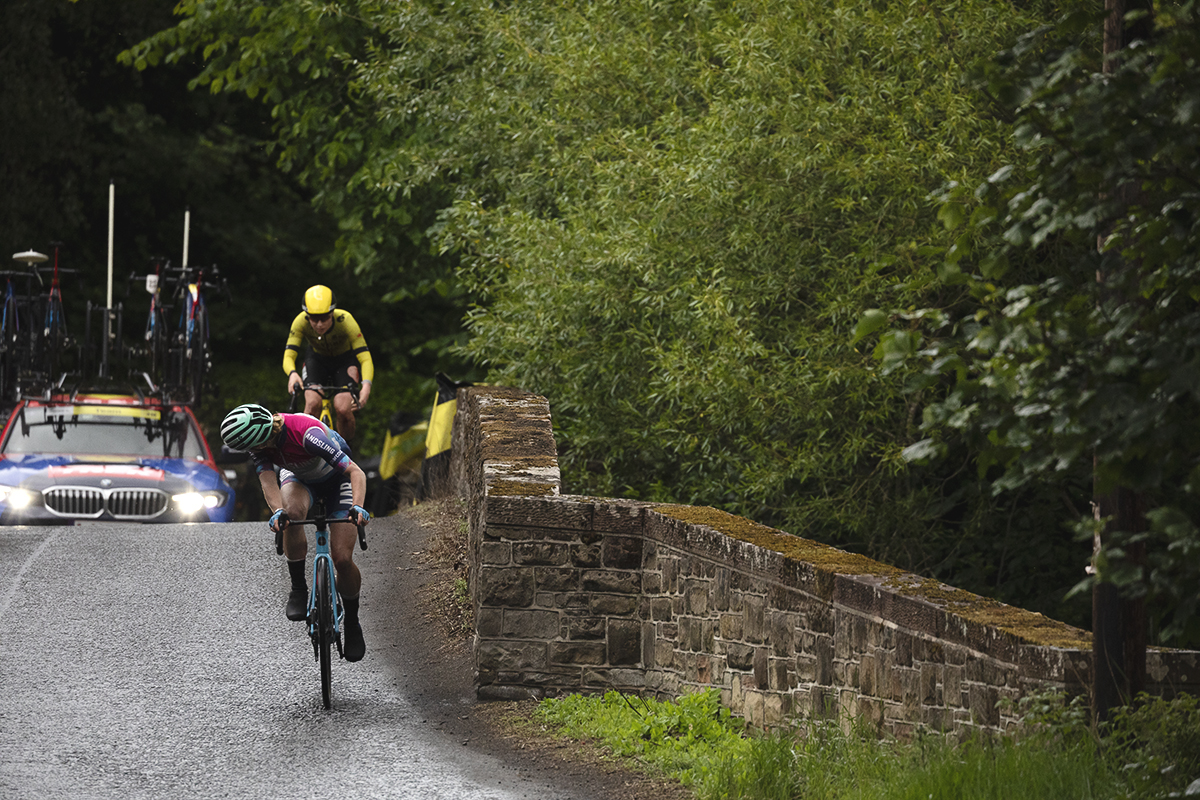Tour of Britain Women’s 2025 - Stage 3 - A rider looks behind at a rival on the bridge at Leaderfoot