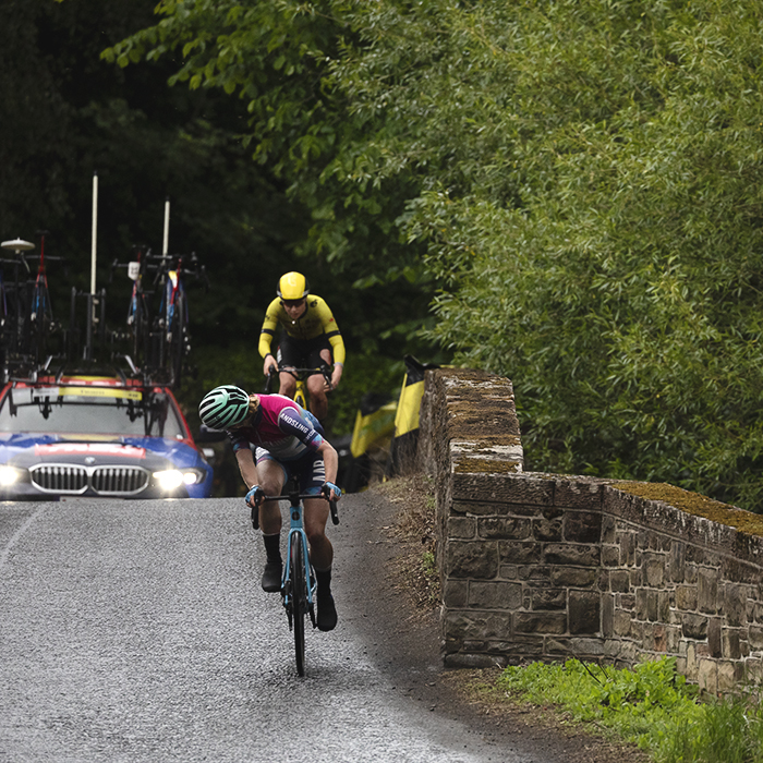 Tour of Britain Women’s 2025 - Stage 3 - A rider looks behind at a rival on the bridge at Leaderfoot