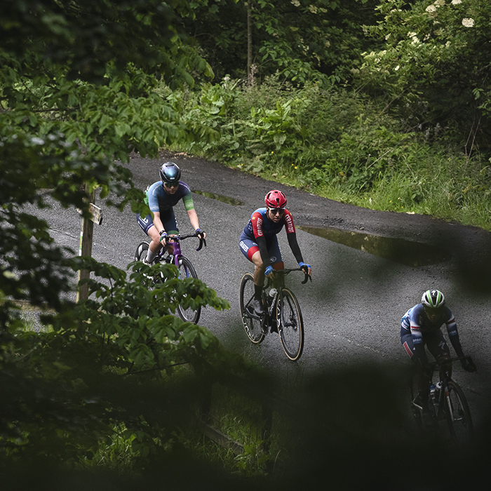 Tour of Britain Women’s 2025 - Stage 3 - Riders framed by trees at Leaderfoot