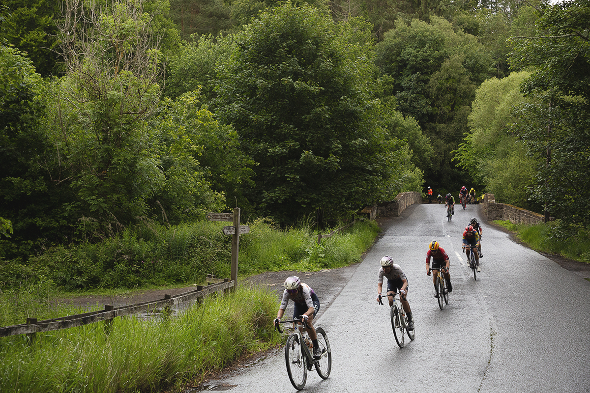Tour of Britain Women’s 2025 - Stage 3 - A line of riders cross a bridge at Leaderfoot