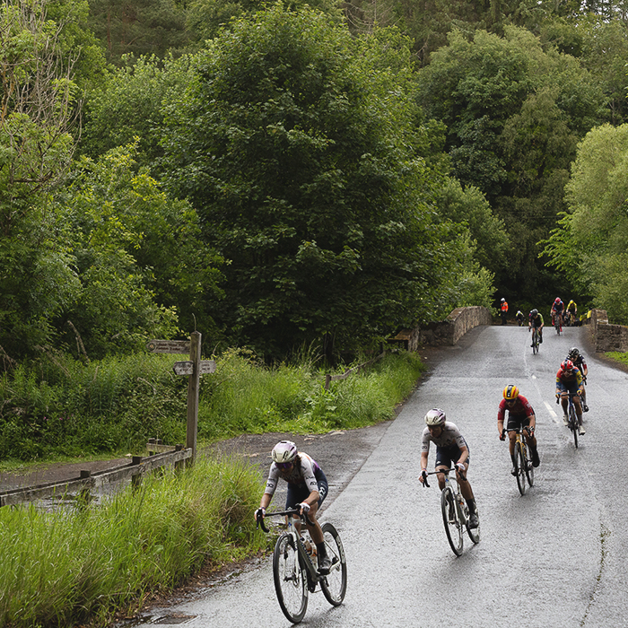 Tour of Britain Women’s 2025 - Stage 3 - A line of riders cross a bridge at Leaderfoot
