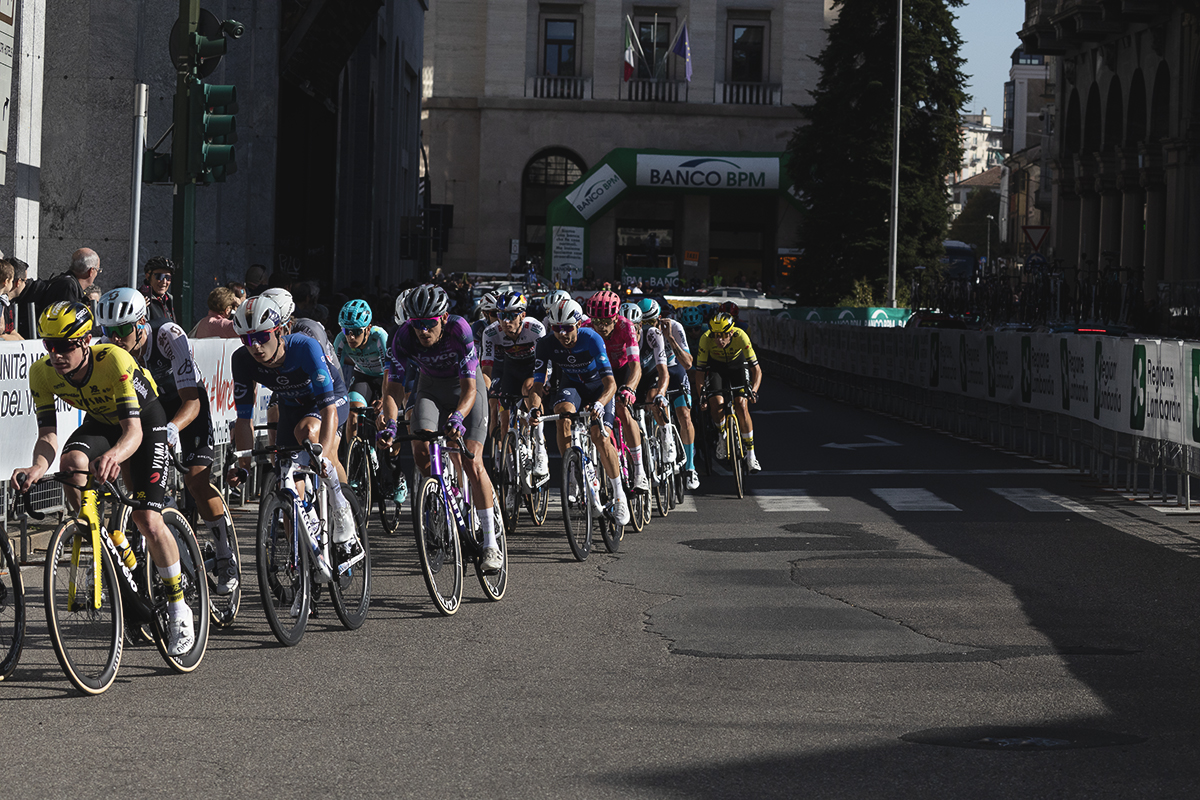 Tre Valli Varesine 2025 - Riders pass by commercial buildings in Varese