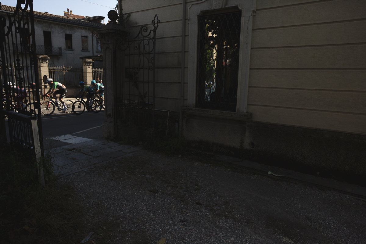 Tre Valli Varesine 2025 - Riders seen through ornate iron gates in Varese