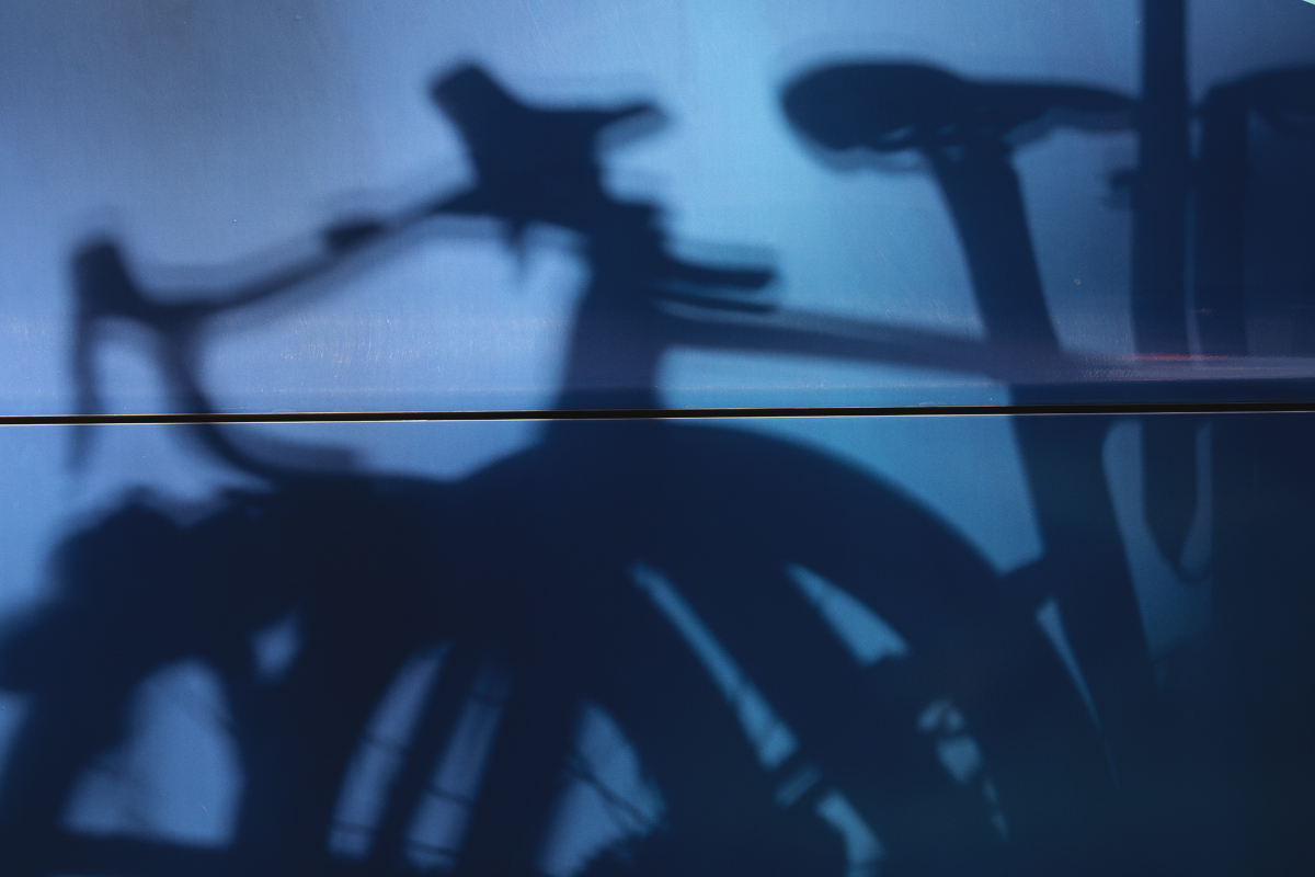 Tre Valli Varesine 2025 - A Shadow of race bikes is cast in the side of a team bus