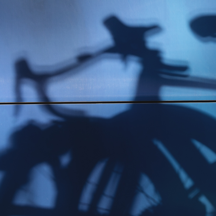 Tre Valli Varesine 2025 - A Shadow of race bikes is cast in the side of a team bus