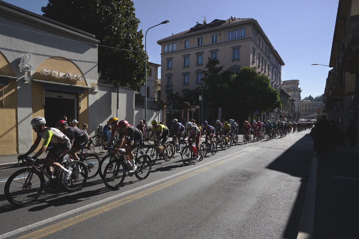 Tre Valli Varesine 2025 - The peloton passes by a gelato shop in central Varese
