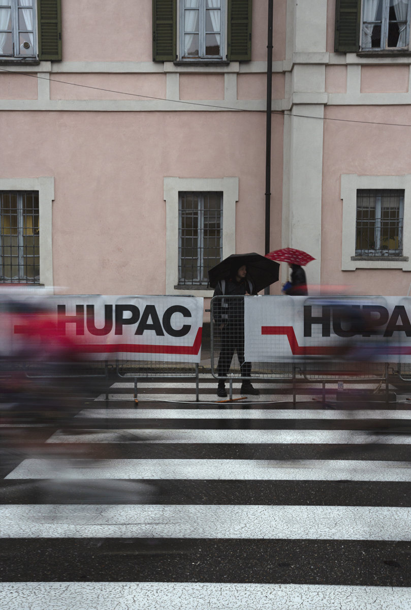 Tre Valli Varesine Women’s Race 2024 - Spectators sheltering under umbrellas watch the riders come into the finish