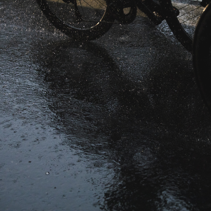 Tre Valli Varesine Women’s Race 2024 - The shadow of a bike wheel with spray coming up from its wheel in Varese