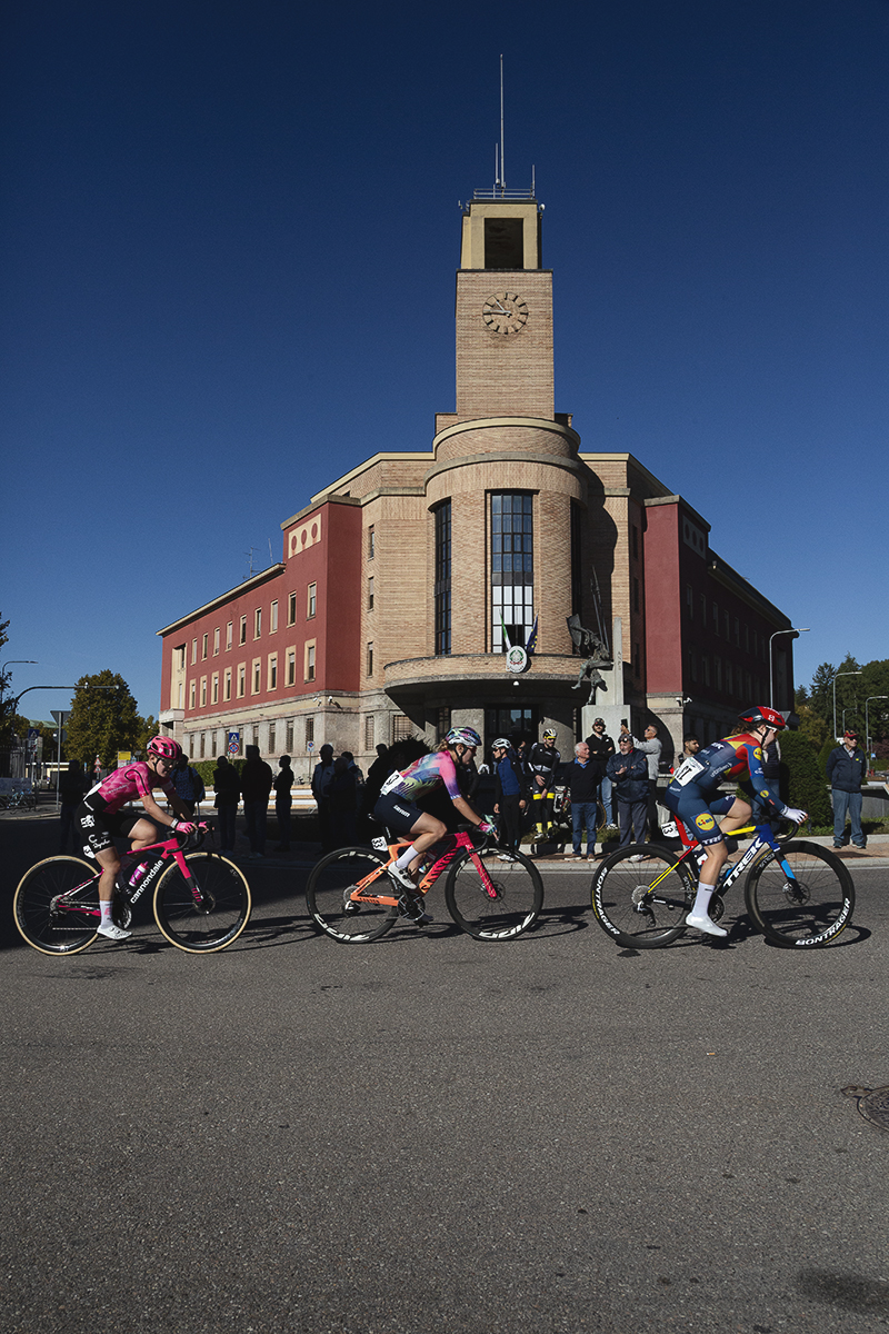 Tre Valli Varesine Women’s Race 2025 - A group of riders pass the art deco style local police headquarters