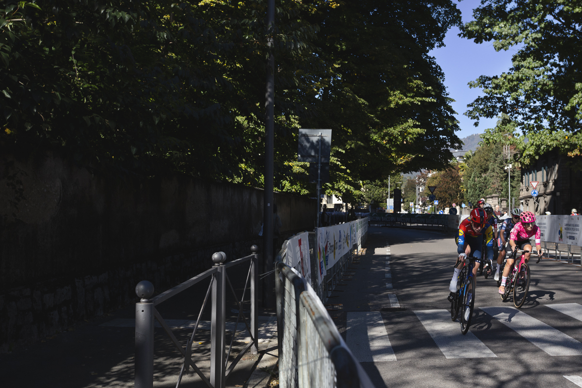 Tre Valli Varesine Women’s Race 2025 - A group of riders round a corner on a tree lined street