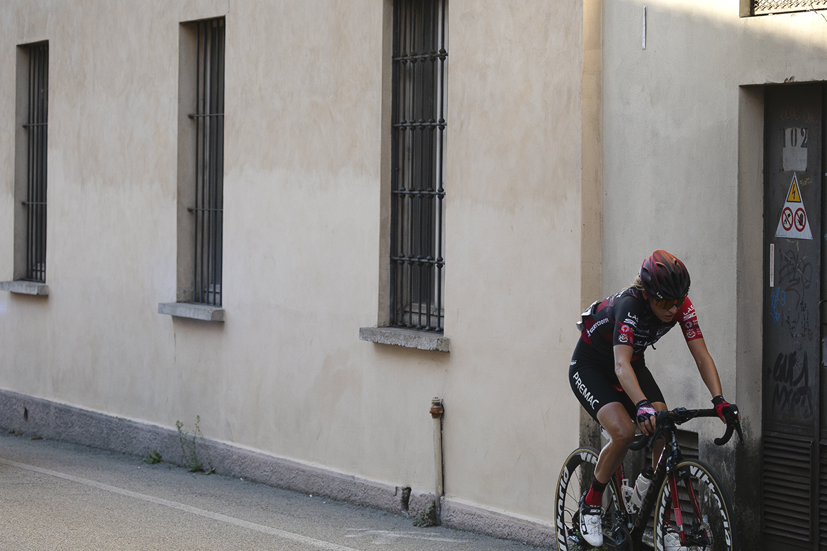 Tre Valli Varesine Women’s Race 2025 - Valeria Curnis rides past a building finished in cream coloured render