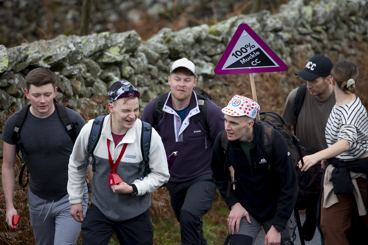 UK National Hill Climb Championships 2023 - A group of fans carry a road sign that reads 100% Muckle